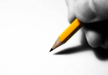 Person schreibt mit Bleistift auf Blatt Papier